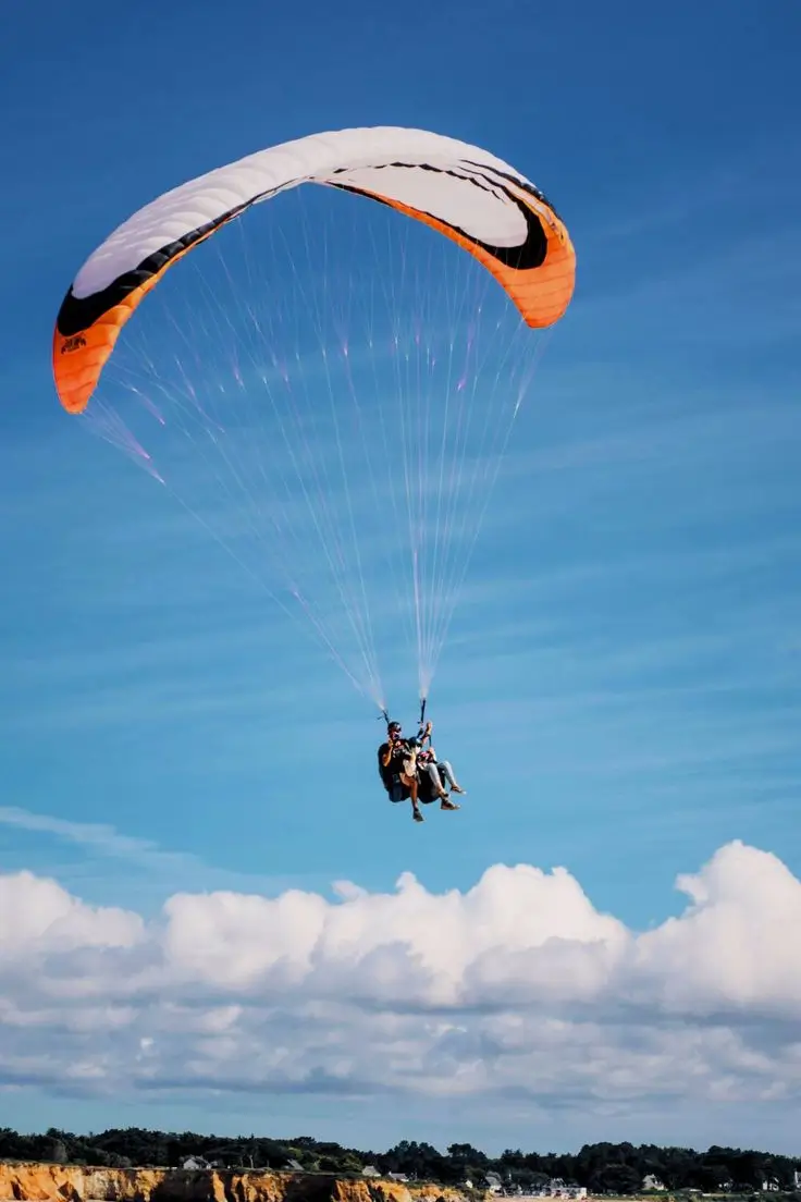 Tandem paraglider lifting off from the ridge